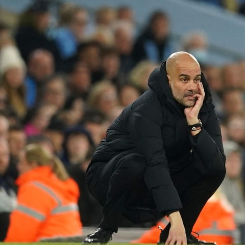 Pep Guardiola, Trainer von Manchester City, hockt an der Seitenlinie und studiert das Spiel seiner Mannschaft.