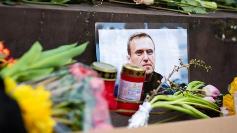 Blumen und Kerzen liegen vor einem Bild von Alexej Nawalny.