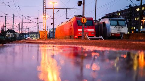 Eine Lok der Deutschen Bahn DB steht im Hauptbahnhof Hannover und spiegelt sich in einer Wasserfläche auf dem Bahnsteig.