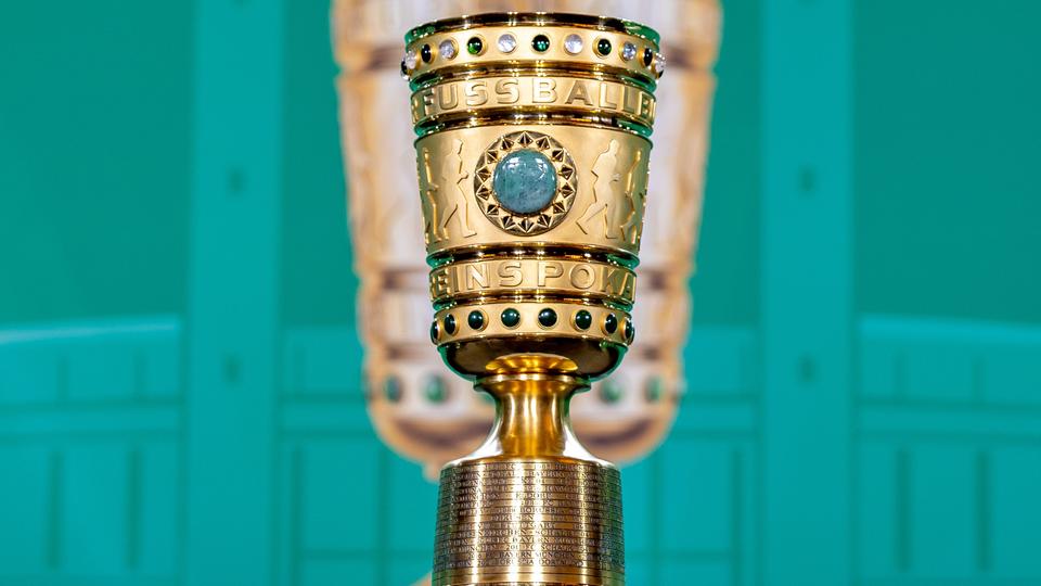 Der DFB-Pokal steht auf einem Sockel vor einer grünen Wand