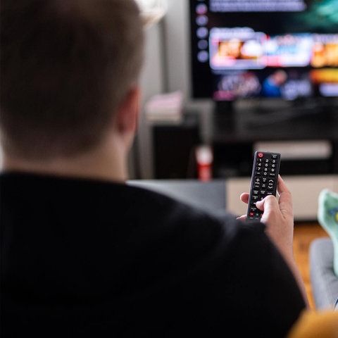 Zwei Menschen mit Fernbedienung vor einem Fernseher.