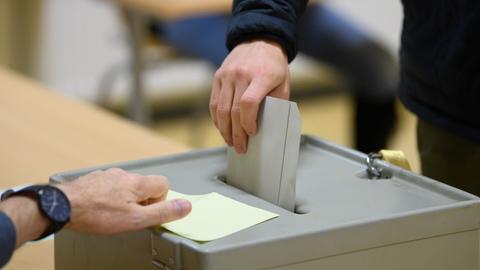 Ein Wähler wirft bei der Stimmabgabe im Wahllokal seinen Stimmzettel in eine Wahlurne.