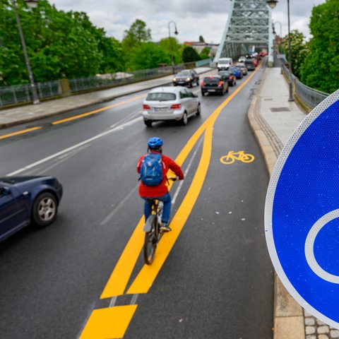 Ein Radfahrer fährt an der Elbbrücke Blaues Wunder auf einem markierten Radweg.