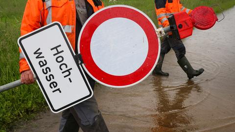 Mitarbeiter der Stadt Riedlingen stellten Absperr- und Hinweisschilder mit der Aufschrift "Flut"auf einem vom Regen überfluteten Radweg. 