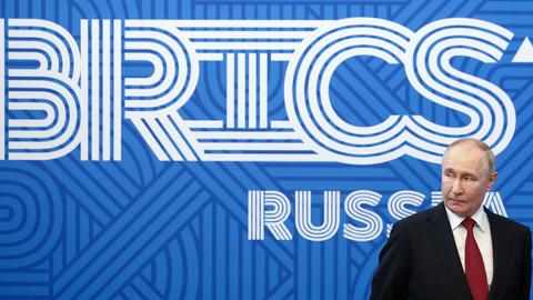 Der russische Präsident Putin vor einem Plakat mit den Lettern BRICS.