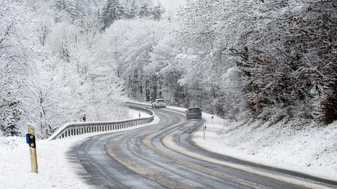 Autos fahren über eine verschneite Landstraße.