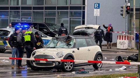 Polizisten stehen neben einem Auto an einem Tatort in München.