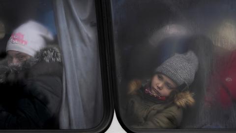  Zwei Kinder, die mit anderen Flüchtlingen aus der Ukraine unterwegs sind, schauen aus dem Fenster eines Busses in der Nähe des Grenzübergangs in Medyka, Polen.  (dpa)