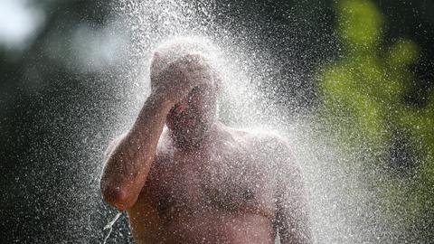 Ein Mann steht an einem Badesee unter einer Dusche (dpa)