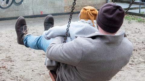 Ein Vater spielt mit seinem Kind auf einem Spielplatz. 