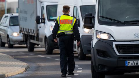 Ein Polizist hält auf der Grenzbrücke zwischen Deutschland und Polen Fahrzeuge an.