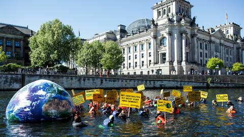 Aktivisten der Umweltschutzorganisation Greenpeace schwimmen am Reichstag in der Spree in Berlin. Mit der Aktion will die Organisation für mehr Klimaschutz demonstrieren. (dpa)