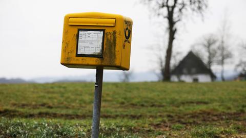 Ein Briefkasten steht vor einer Wiese.