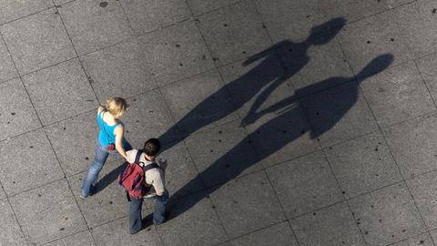 Ein Paar hält sich beim Spazierengehen an den Händen und wirft dabei lange Schatten