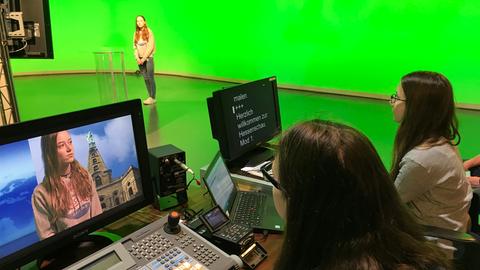 Dre Mädchen probieren im Fernsehstudio aus, wie Regiepult, Teleprompter und Moderation funktionieren.