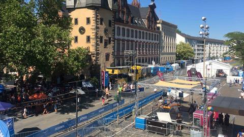 Blick vom Eisernen Steg: Vorne die Moderationsplattform direkt an der Laufstrecke, im weißen Zelt dahinter die Wechselzonefür die Athleten vom Rad zum Marathon. Oben im Bild: Der gesamte TV-Compound der Produktionsfahrzeuge am Mainkai. 