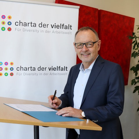 hr-Intendant Manfred Krupp unterzeichnet beim Unterzeichnen der Urkunde t die "Charta der Vielfalt"